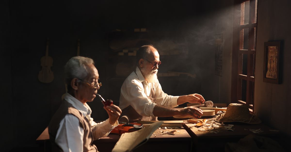 Artisans crafting violins in a traditional Jakarta workshop with natural light.