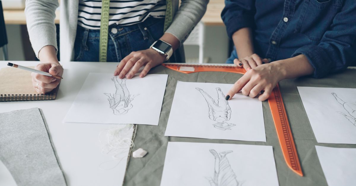 Designers working together on fashion sketches, coordinating design ideas.