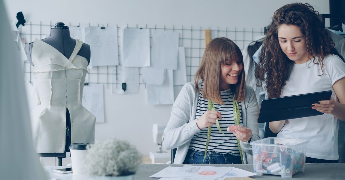 Two fashion designers working together in a studio, designing a new dress.