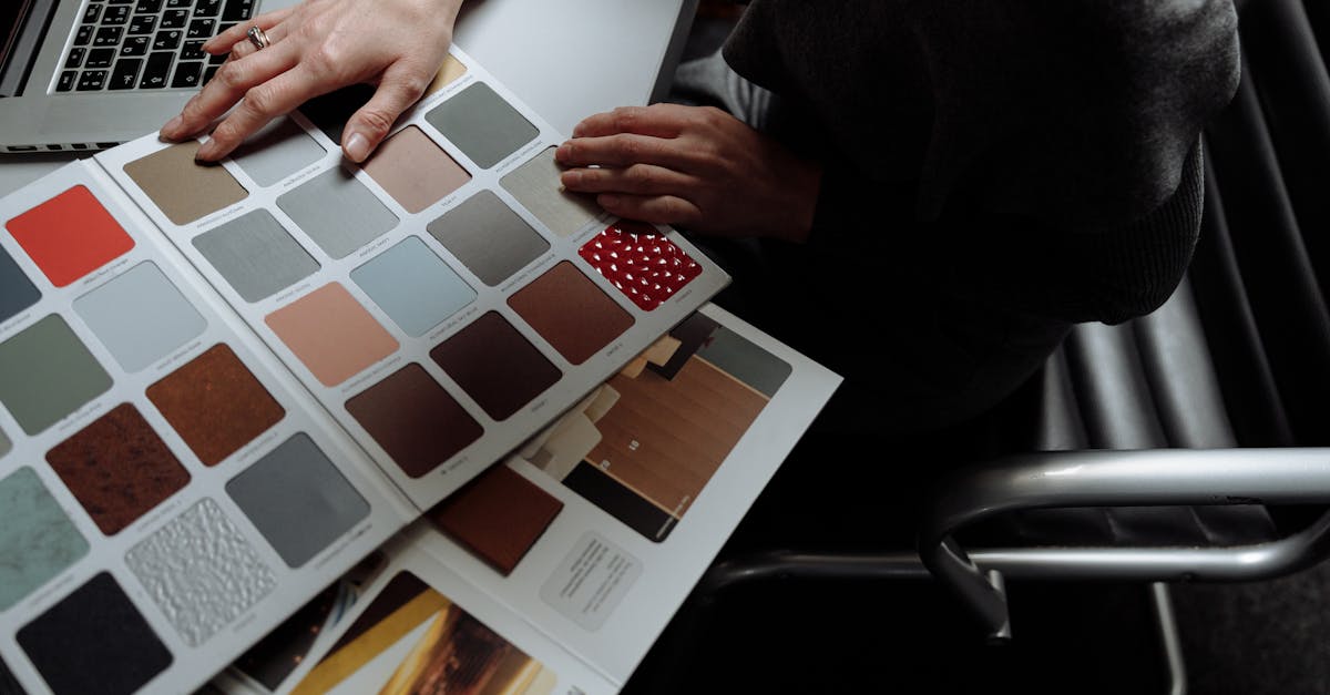 Interior designer on laptop reviewing color swatches for design project. Overhead view, modern workspace.