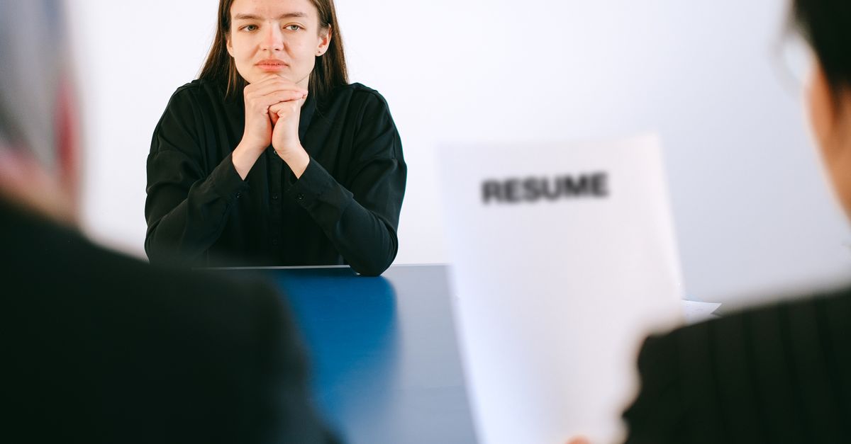 A woman in a job interview facing two employers with a focus on her resume.