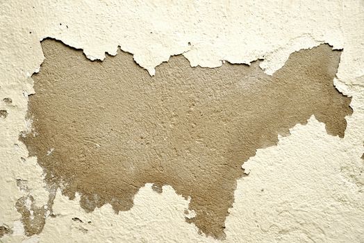 Close-up of a wall with peeling paint revealing the rough texture underneath.