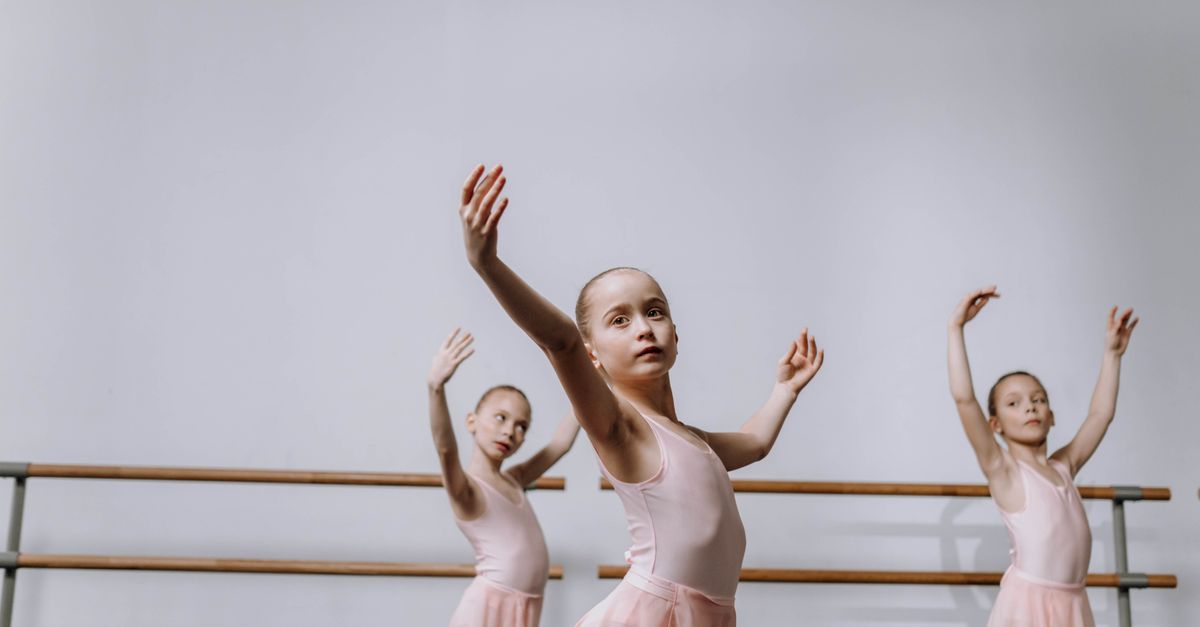 Three young ballerinas in pink tutus practice in a ballet studio, showcasing graceful choreography.