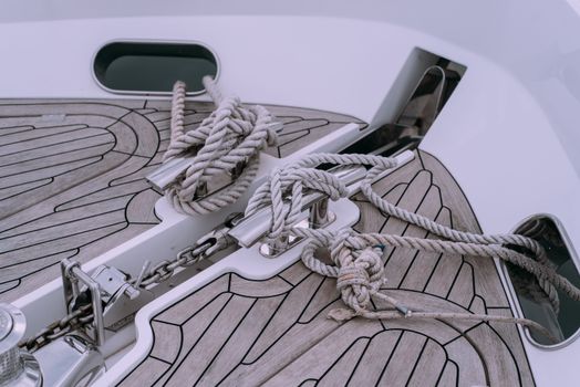 Detailed view of knotted ropes and chains on a boat deck, showcasing nautical materials.