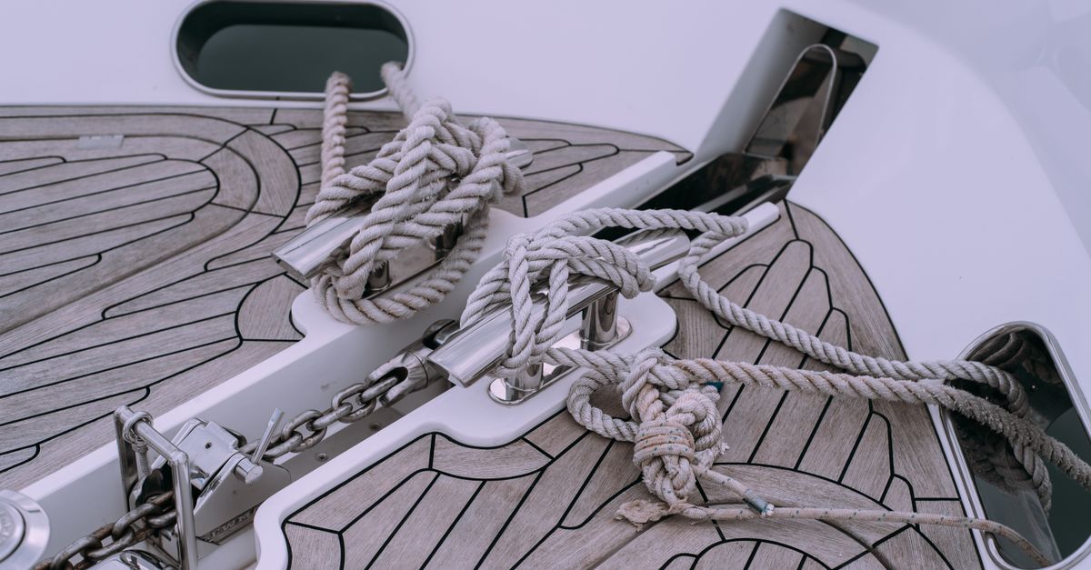 Detailed view of knotted ropes and chains on a boat deck, showcasing nautical materials.
