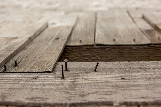 Detailed view of weathered wooden boards and nails, showcasing rustic texture.