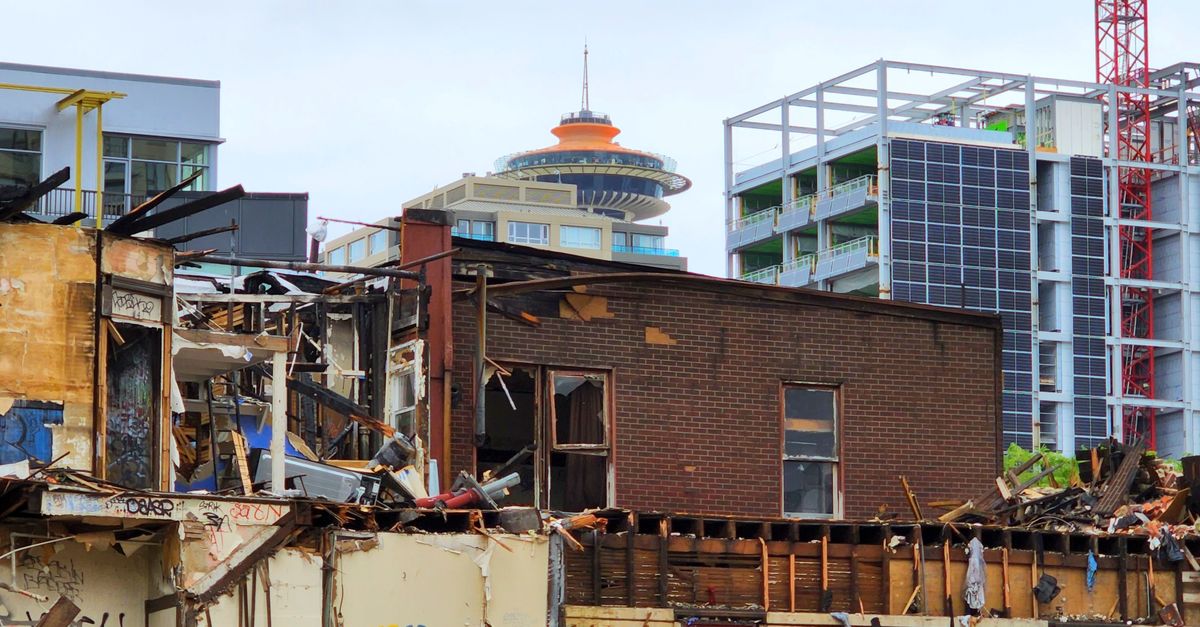 An urban demolition site with a mix of old and modern architecture in the background.