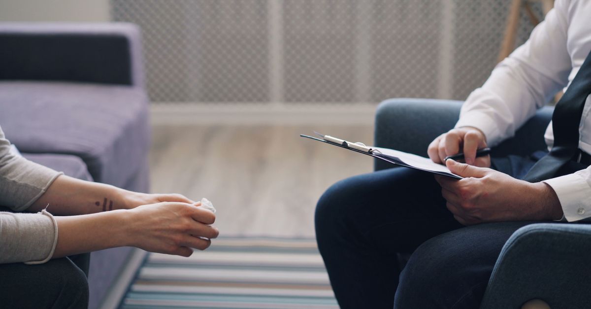 A therapy session with a psychologist and patient, discussing mental health indoors.