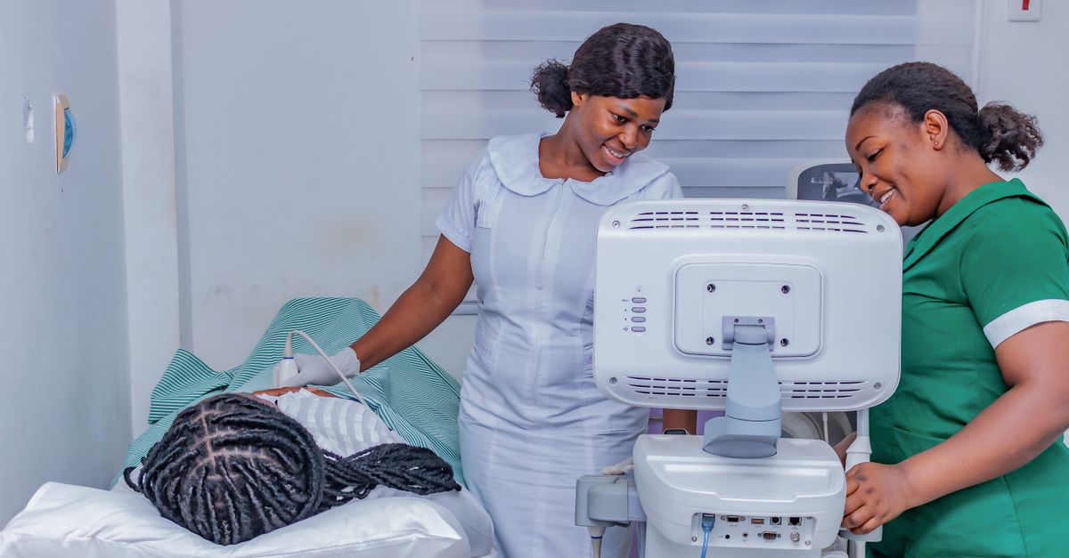 Smiling healthcare professionals performing an ultrasound examination in a clinical setting.