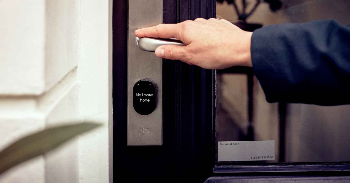 A hand opening a smart home door with digital access panel, conveying security and technology.