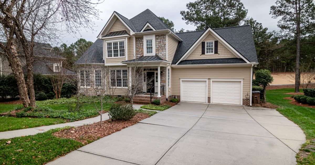 Charming suburban home featuring a two-car garage, manicured lawn, and inviting entrance.