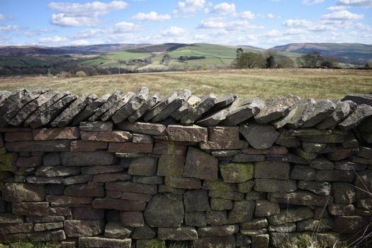 Beautiful English countryside landscape with traditional dry stone wall and rolling hills.