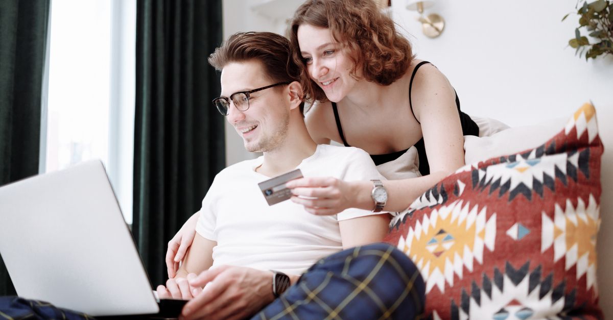 Happy couple using laptop for online shopping while sitting together at home.
