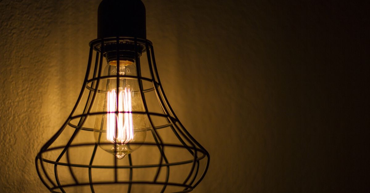 Close-up of a vintage Edison bulb inside a wire cage fixture casting warm light.