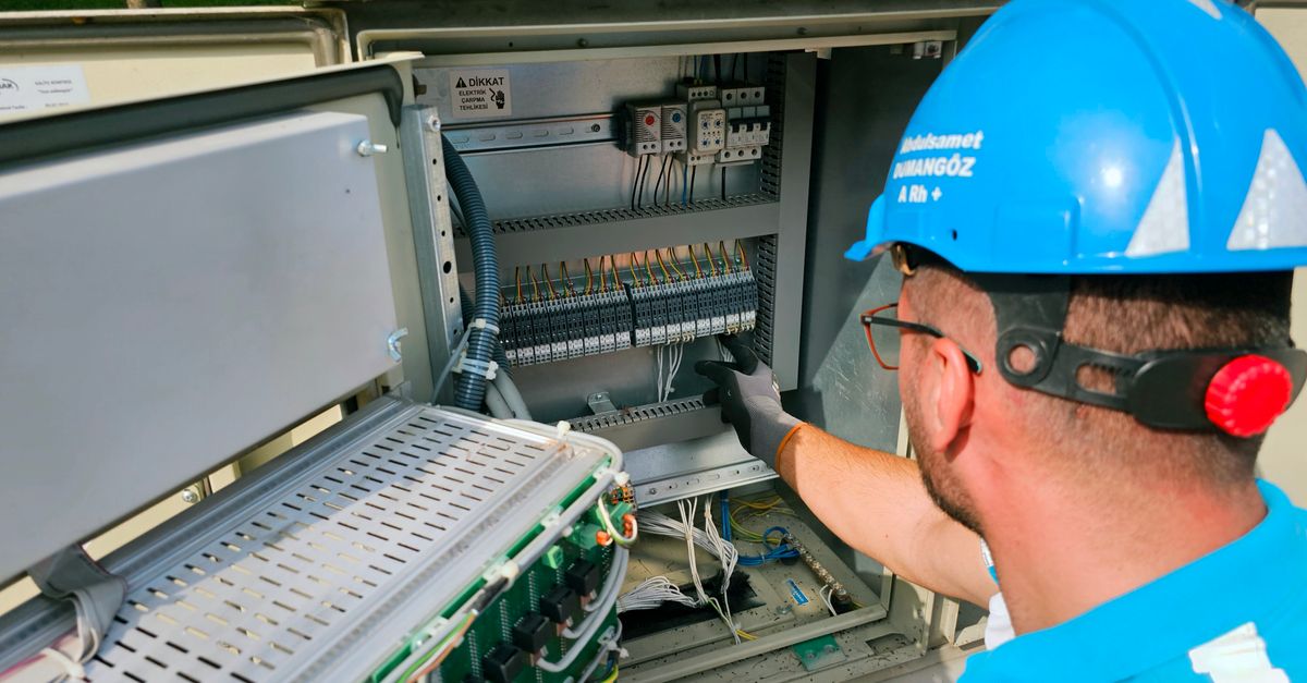 An electrician works on an outdoor fusebox, ensuring safety and functionality.