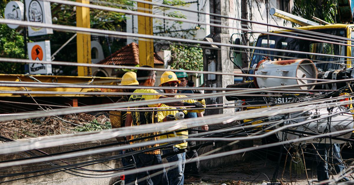 Utility workers repairing downed power lines amidst damaged infrastructure. Outdoor setting with chaos.