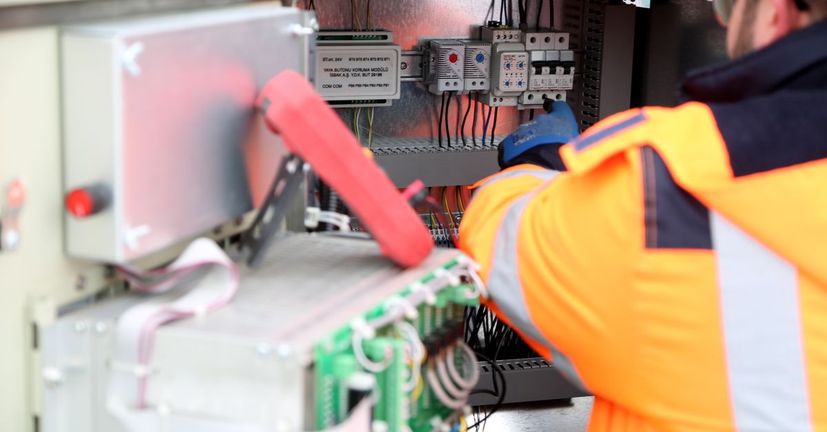 Professional engineer inspecting industrial electrical circuit board, ensuring safety standards.