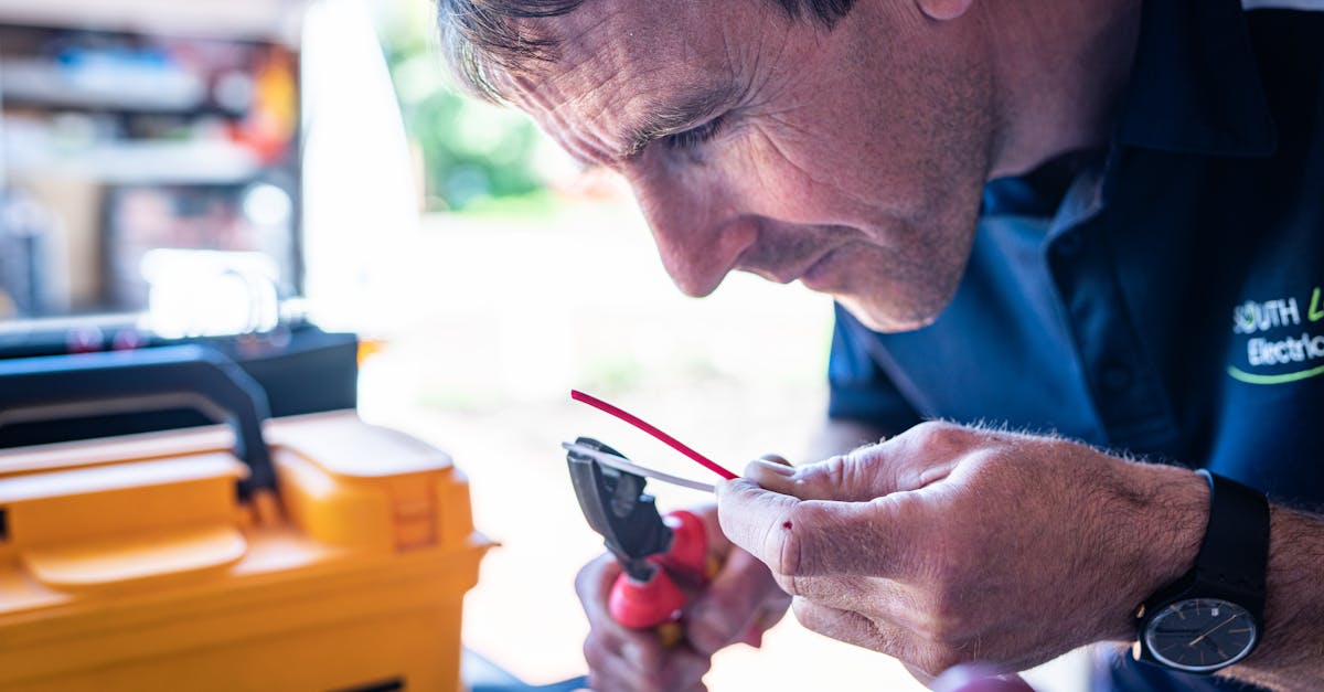 Focused technician working on wiring with tools in a workshop setting.