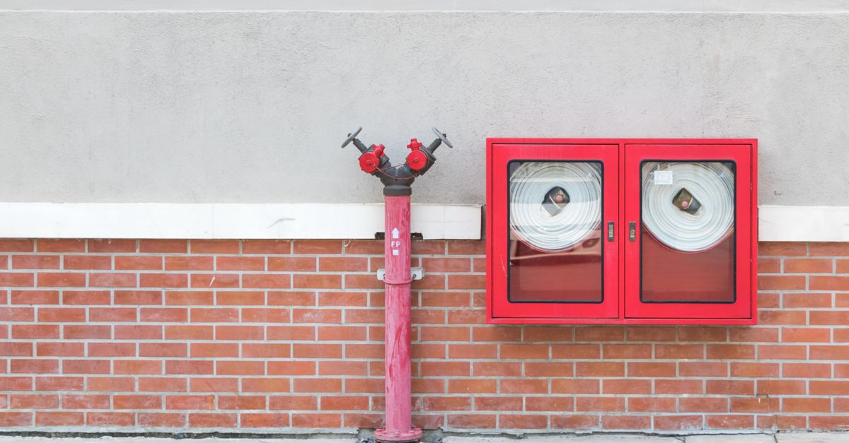 Outdoor fire hydrant and hoses against a brick wall, emphasizing fire safety.
