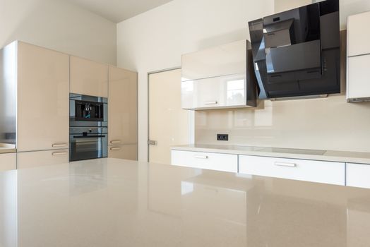 Sleek and spacious modern kitchen design featuring glossy cabinets and high-end appliances.