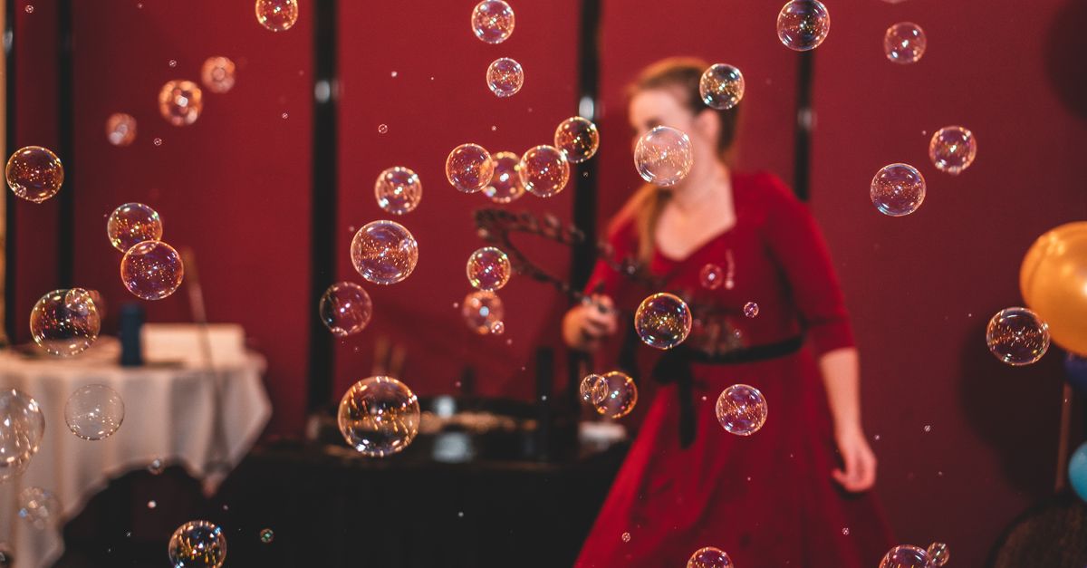 Indoor celebration with colorful bubbles floating around a person in a red dress.