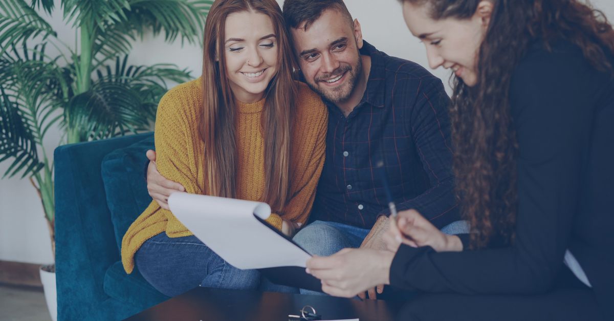 Happy couple discussing finance with advisor in cozy office setting.
