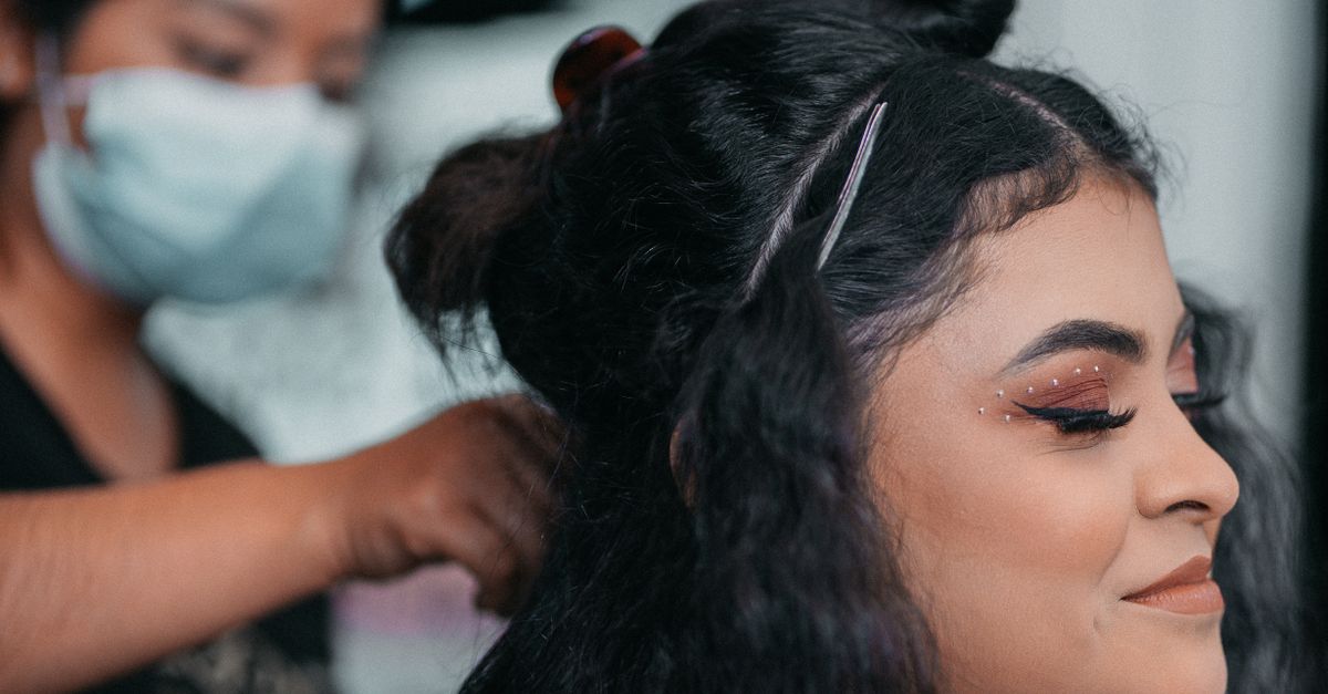 Close-up of professional hair styling at a salon with a focus on makeup artistry.