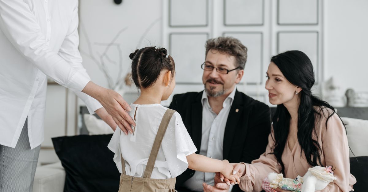 A touching moment between prospective parents and a child at an adoption center indoors.