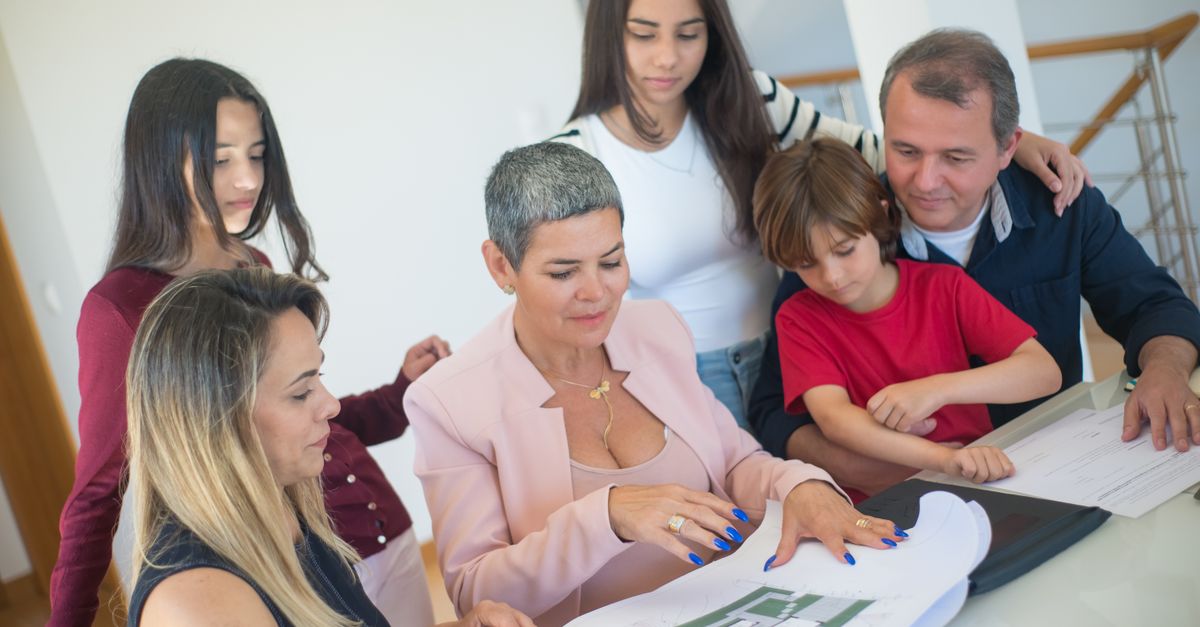 A family discusses property plans with a realtor indoors, focused on purchasing a new home.