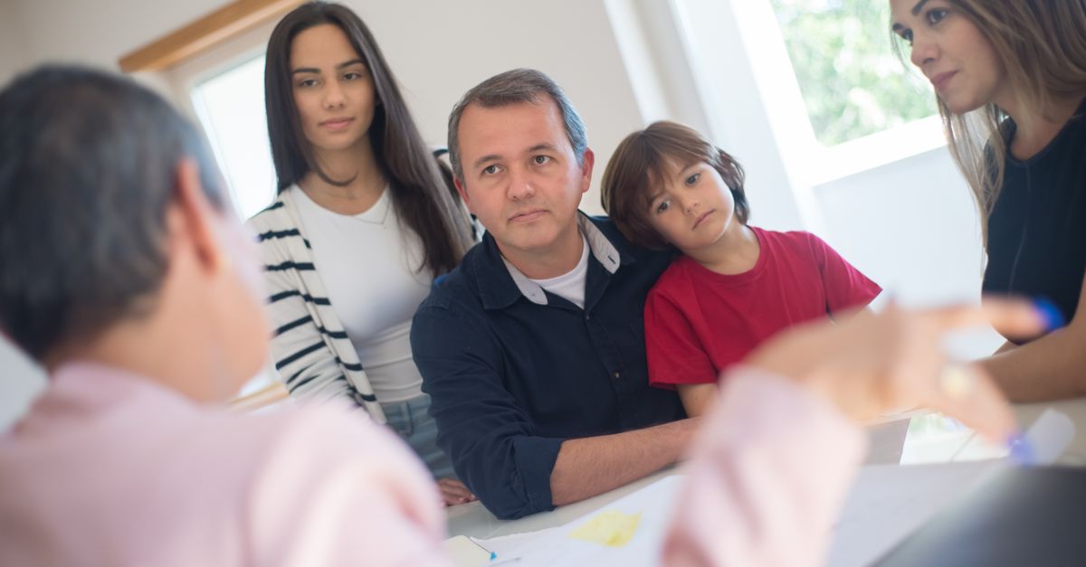 A family of four seeks advice from a professional during an indoor consultation in a bright room.