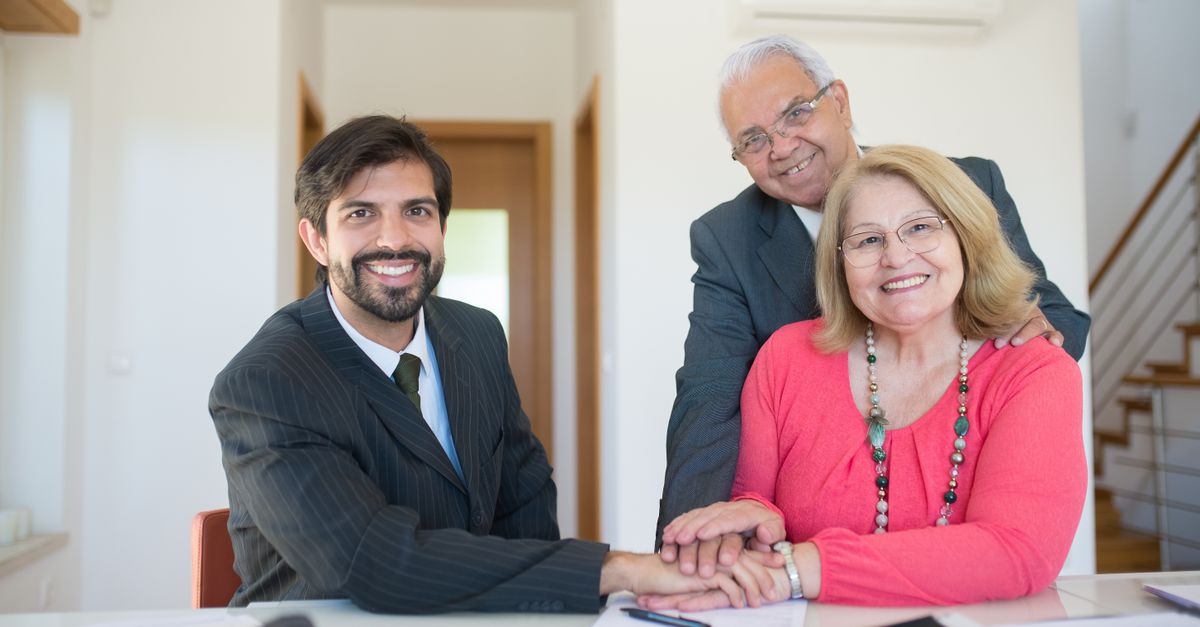 Smiling senior couple meeting with a professional advisor in a bright indoor setting.