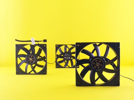Three cooling fans are arranged on a vibrant yellow background, emphasizing tech design.