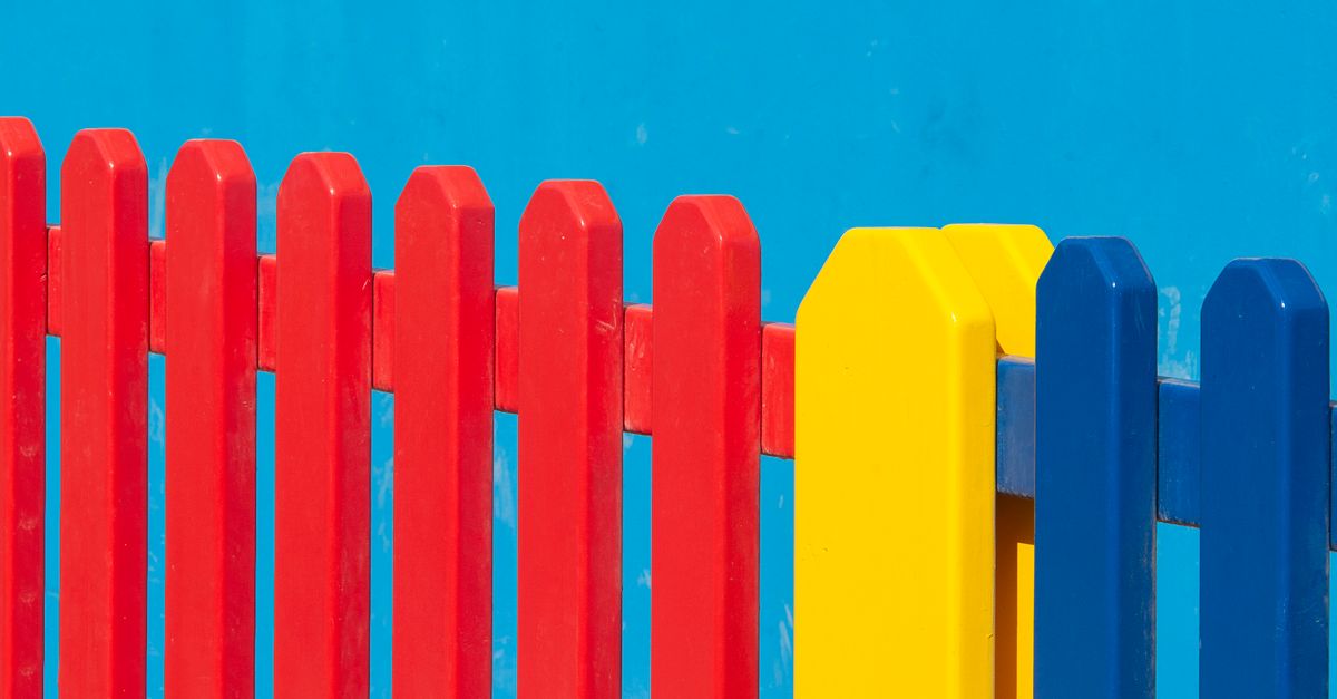Vibrant red, yellow, and blue wooden fence panels against a clear blue backdrop.