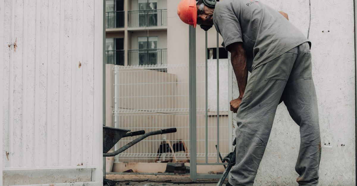 Man in hard hat operating a jackhammer on an outdoor construction site.