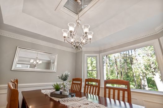 Beautiful dining room featuring a classic chandelier, wooden furniture, and ample natural light from large windows.