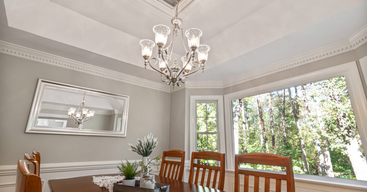 Beautiful dining room featuring a classic chandelier, wooden furniture, and ample natural light from large windows.
