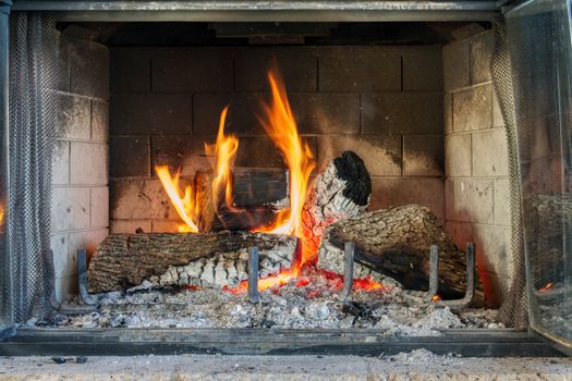 Warm and inviting indoor fireplace with glowing firewood and vibrant flames.