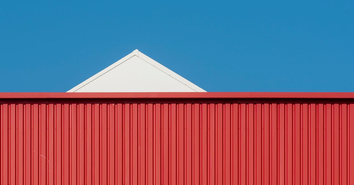 A minimalist photo of a red and white building against a clear blue sky.