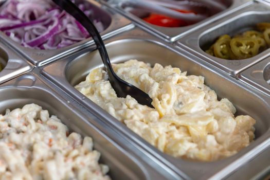 Delicious creamy potato salad ready to serve in a buffet setting. Perfect for lunch or dinner.