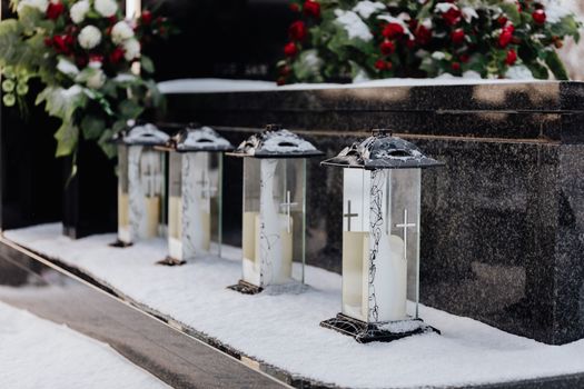 Cemetery lanterns in snow, creating a serene winter memorial scene.