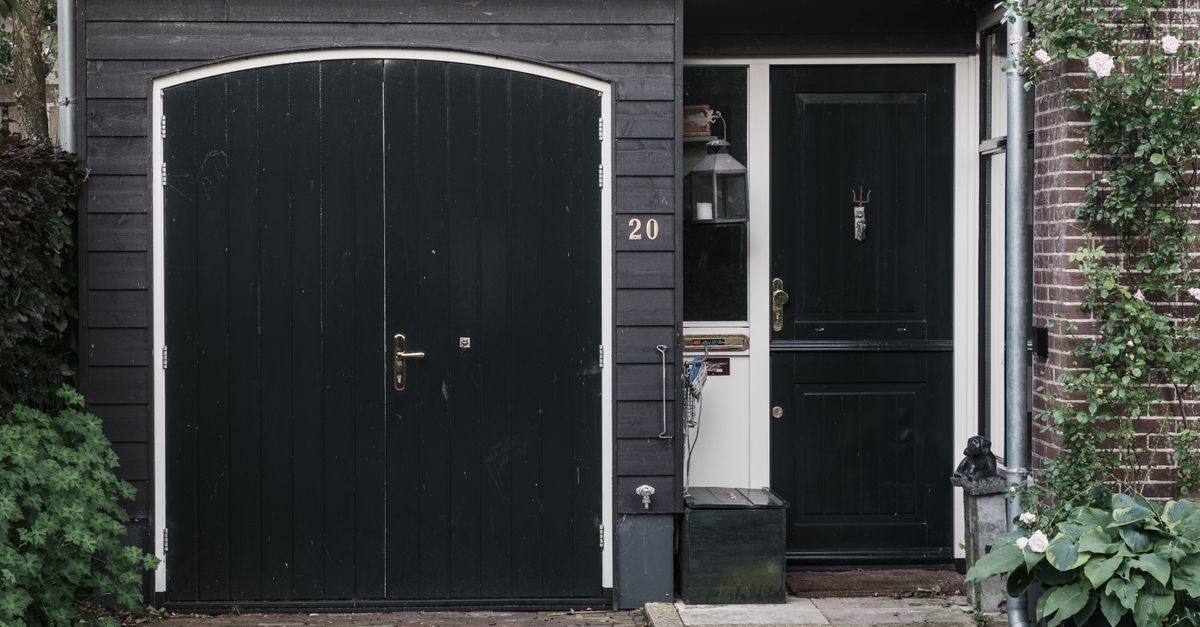 Exterior of a traditional Dutch house with black doors and a landscaped garden.