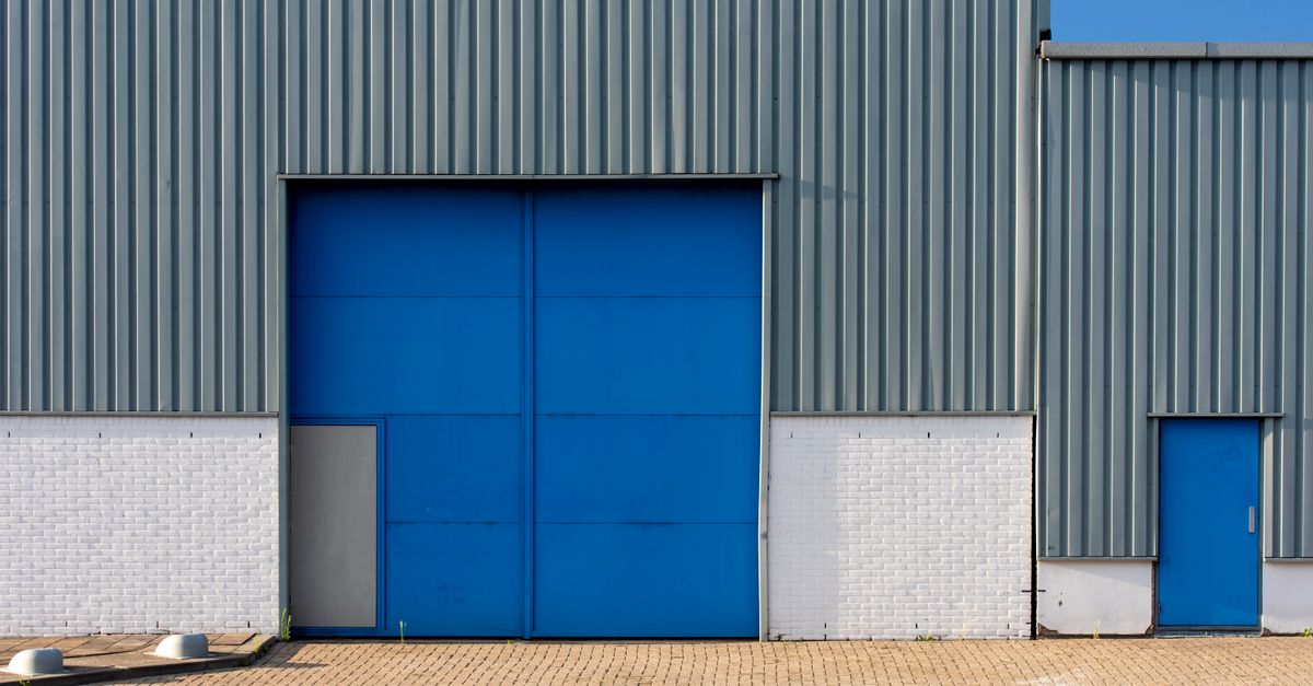 Front view of a blue and gray metal warehouse exterior with large doors.