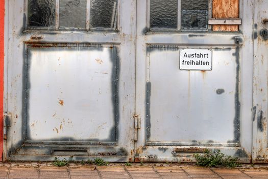 Weathered garage door with a German sign reading 'Keep Exit Clear.'