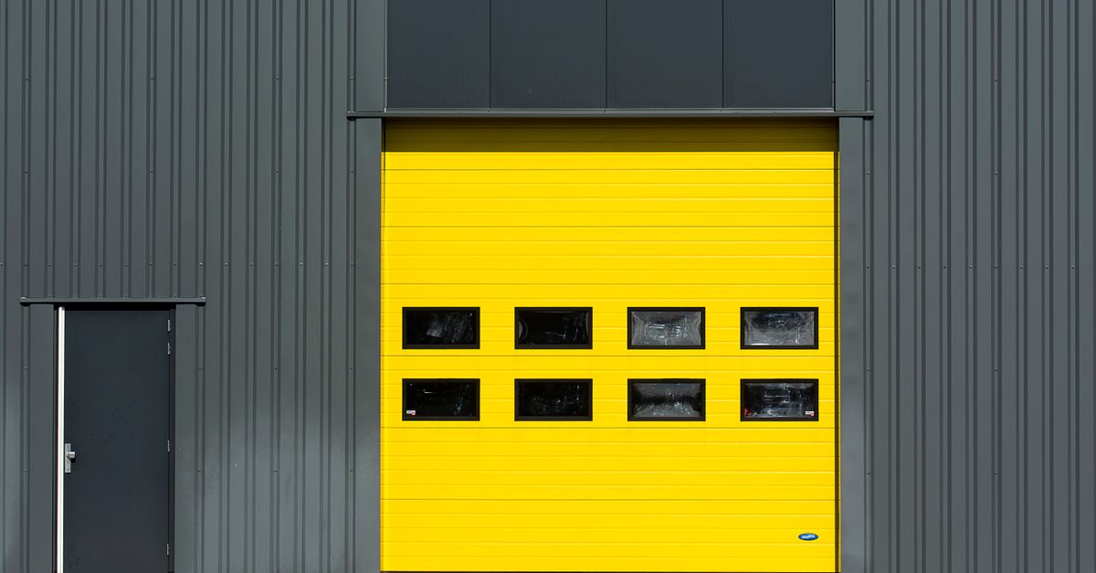 A sleek industrial structure featuring a vibrant yellow garage door for architectural interest.