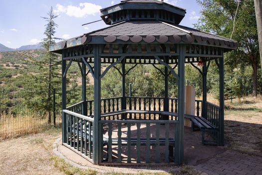 A charming wooden gazebo set amidst the lush greenery of Bingöl, Türkiye, on a sunny day.