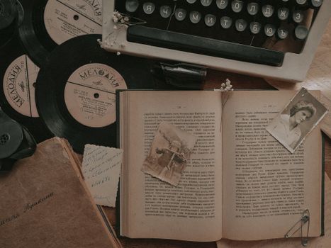 A nostalgic still life featuring a typewriter, vinyl records, and an open book.