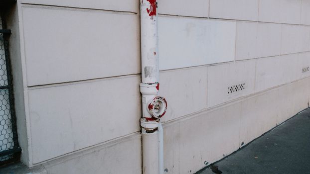 Close-up of a weathered drainpipe on an urban wall, showing signs of wear.