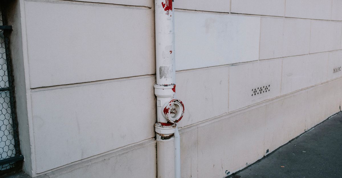 Close-up of a weathered drainpipe on an urban wall, showing signs of wear.