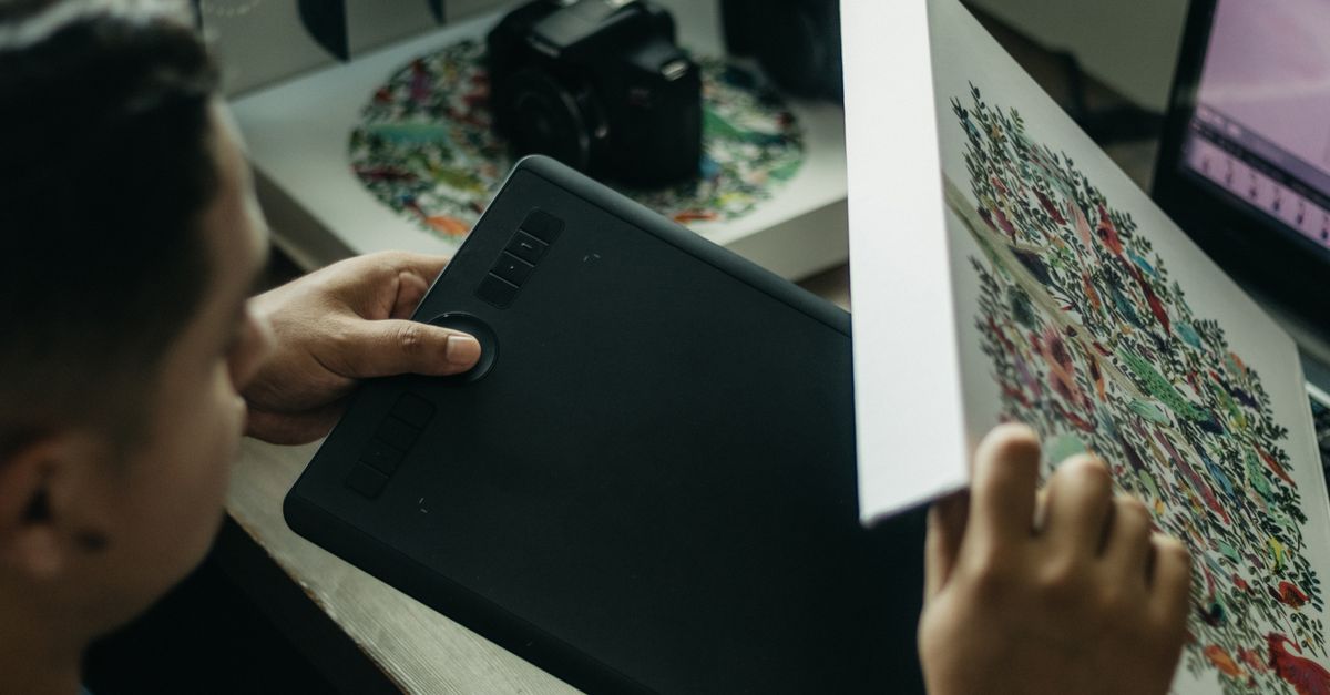 Close-up of a digital artist working with a graphics tablet indoors.