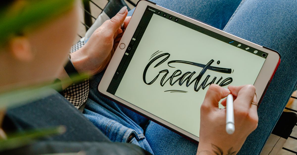 Person using stylus pen on tablet for digital lettering showing creativity in design.